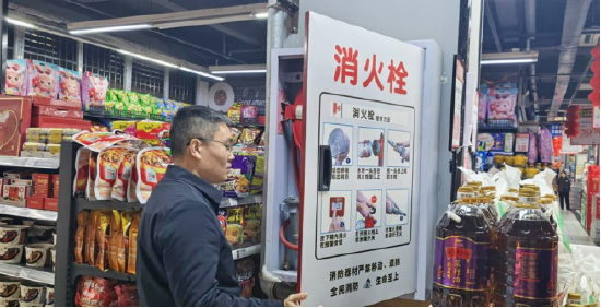 图为：翠屏街道党工委副书记、办事处主任任小强检查世纪隆超市消防设施