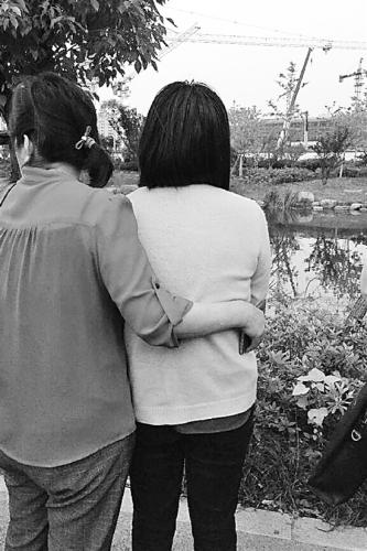 家属守在河道边等待打捞结果,右边是失踪者的妻子王女士。