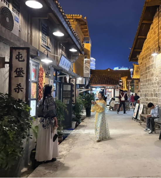 古城街巷，游客身着特色服饰夜游打卡