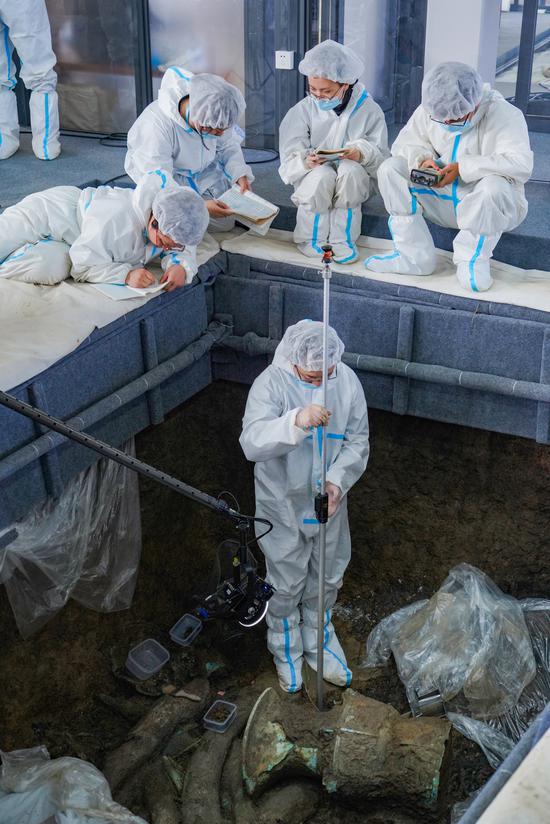 工作人员正在用全球仪，结合全球定位系统，测量器物出土点位。