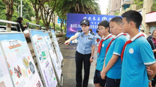 工作人员在禁毒展板前为学生科普防毒知识