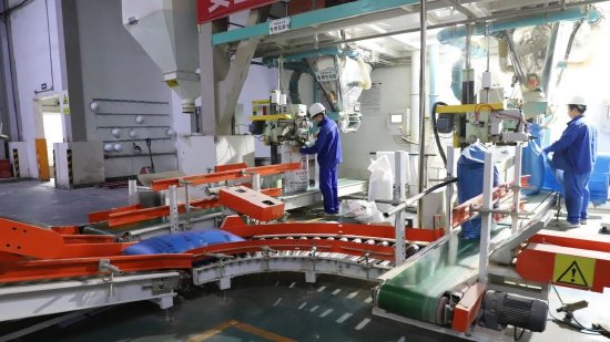 达州禾丰生物科技有限公司生产车间内，工人们正进行投料、打包工作