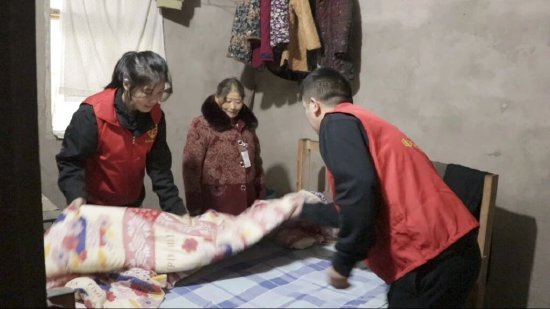 工作人员正为老人换上新棉被