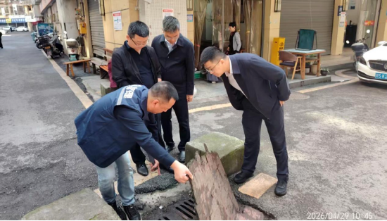 图为：翠屏街道党工委书记和街道办主任带队在草街子社区现场查看排水系统情况