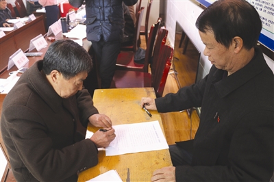 村民大会上,村民签订不大操大办酒席的?#20449;?#20070;(图右为赵纯良)