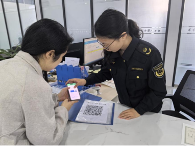 工作人员现场指导群众扫码自助办理业务