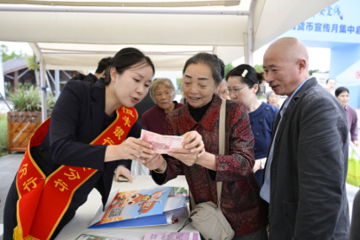 图为：恒丰银行广安分行工作人员为群众讲解人民币知识