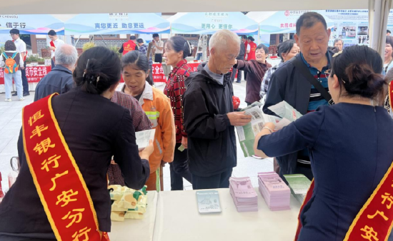 图为：恒丰银行广安分行工作人员为现场群众发放宣传资料