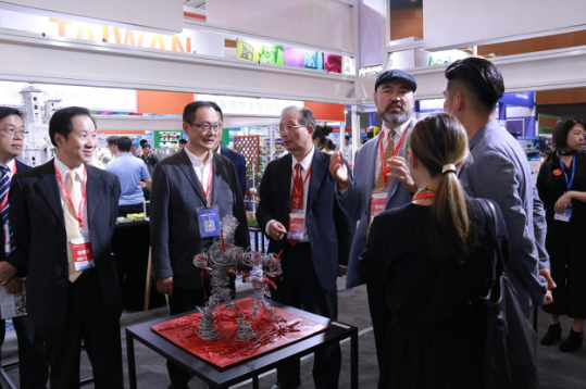 ▲杨梅红艺术教育国际集团创始人王摩希先生亲自为台湾展区领导介绍YMM展区
