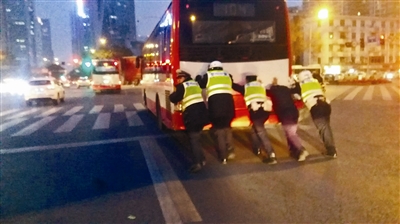 9日傍晚,牛王庙路口,交警三分局辅警们合力将熄火公交车推过路口 图据网友