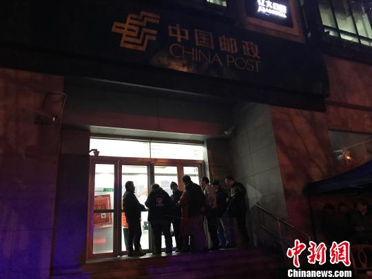1月5日清晨5点半，在上海静安邮政支局，市民冒着寒风与冷雨，撑伞排队，抢购首发的戊戌狗年生肖邮票。　郭容 摄