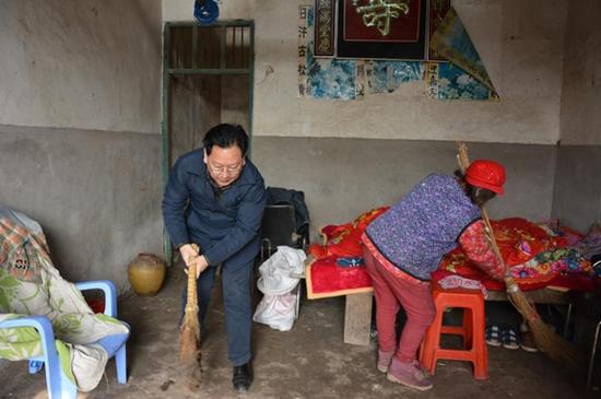 王小铭在贫困户家里帮忙打扫卫生