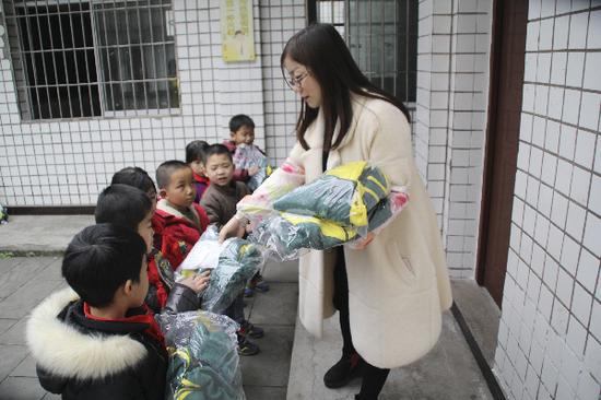 图为大竹县六小老师给同心村小学学生发放校服