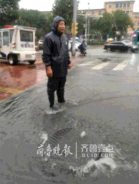 井蓋被頂開，解放路街道城管人員冒雨處置，疏導交通。齊魯晚報·齊魯壹點記者 藍蜂 攝