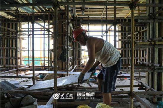 即使避开阳光直射,汗水依旧湿透建筑工人的手套。