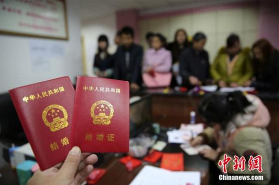 新人在婚姻登记处展示刚领取的结婚证书(图片来源:中国新闻网)