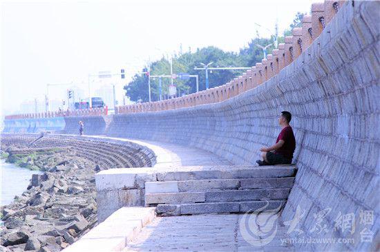 市民在海边的堤坝下乘凉