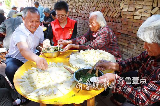 孙敬民（左一）一边包水饺一边陪老人聊天。