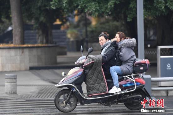 资料图：市民骑行在寒风中。