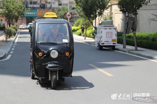 丈夫渠伟盈驾驶电动三轮车载着妻子去送快递