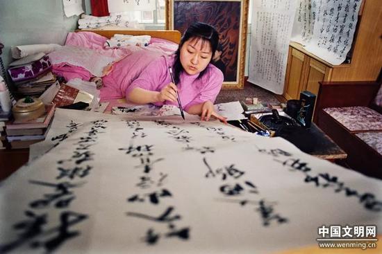 2001年5月，刘晓清趴在床上练习书法。鲁少河摄