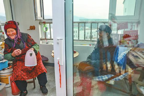 1月1日,王善河坐在新家的陽臺曬太陽,張永蘭起身燒水。