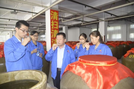 中国白酒大师、古贝春集团总工程师吴兆征(中)和弟子们在地下酒库品尝原酒