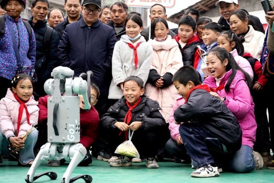 2025年12月6日，四川省巴中市通江县胜利乡新时代文明实践所，学生们与机器狗开展一场别开生面的“人机互动”活动。 程聪 摄