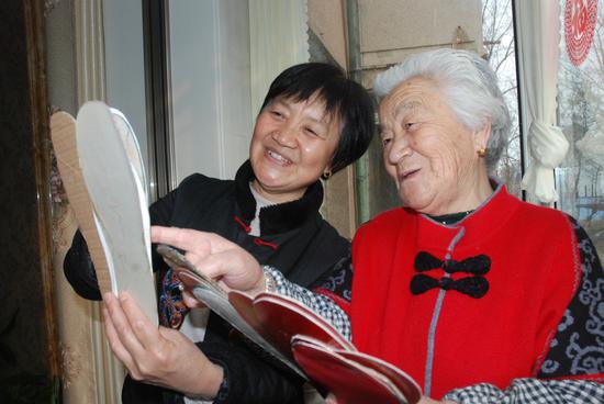 吕爱兰大妈和她的女儿巩昌华在观赏鞋垫式样