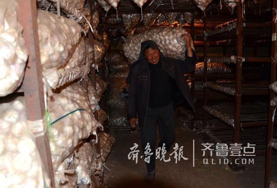 一家冷庫內(nèi),工人們?cè)诎徇\(yùn)大蒜。