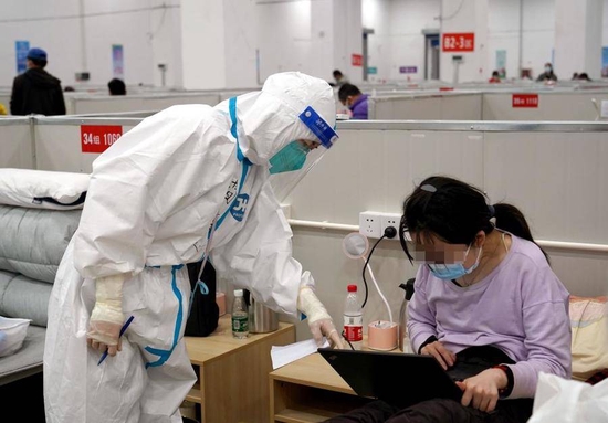 4月21日,上海市临港方舱医院内的医护人员与患者交流。