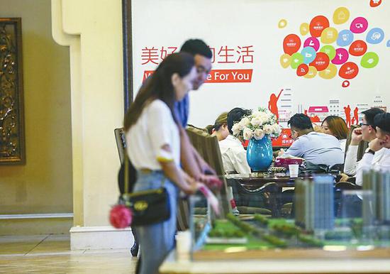 16日,西客站片區一樓盤營銷中心內,中介、銷售人員合力向客戶薦房。