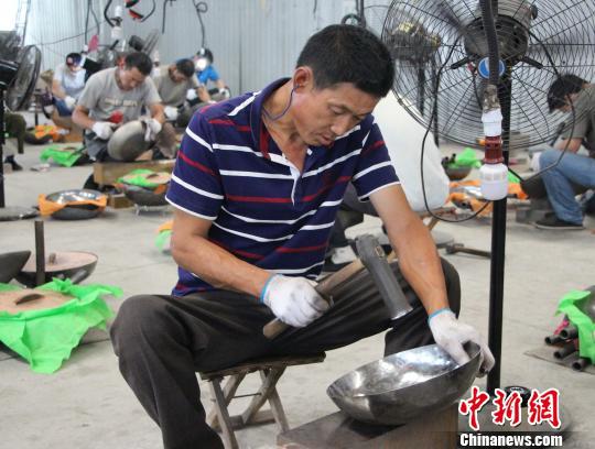 图为匠人们正手持铁锤,打制铁锅。 赵晓 摄