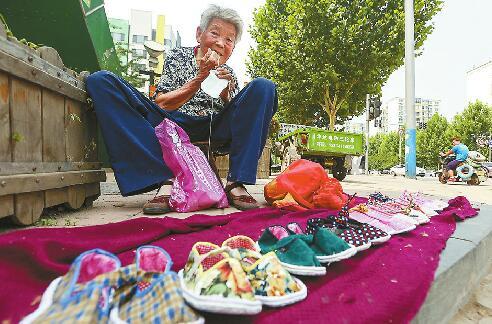 3日，济南阳光100附近，于凤琴一边摆摊一边缝制小布鞋。 记者刘玉乐 摄