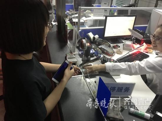 大明湖站首張車票已出票,售票員將車票遞給旅客。