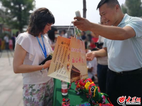 一位外國(guó)友人購(gòu)買(mǎi)非物質(zhì)文化傳承人制作的藝術(shù)品