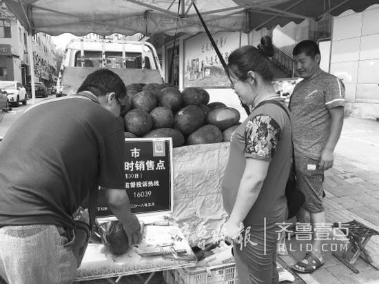 下午近3點,攤位來了顧客,老韋夫妻倆抓緊起身推銷自家的西瓜。