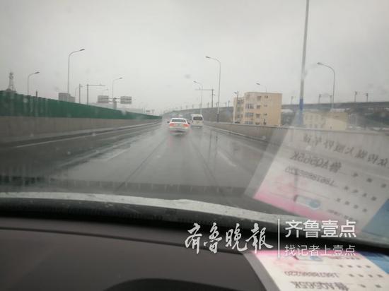 路上有輕微積水,車輛行駛帶起一陣水氣。