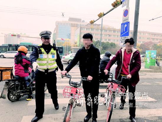 俩小伙并肩骑单车逆行被查。记者张泰来摄