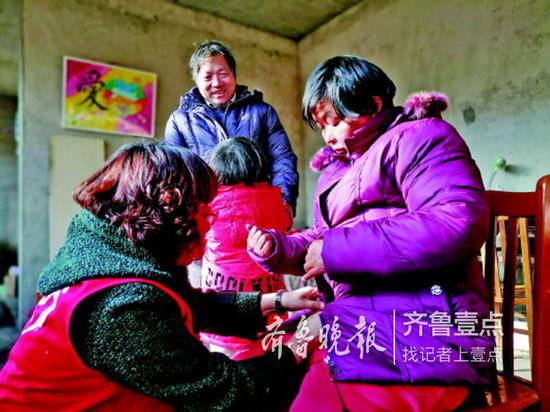 志愿者給時義新的妻子換上新棉衣。