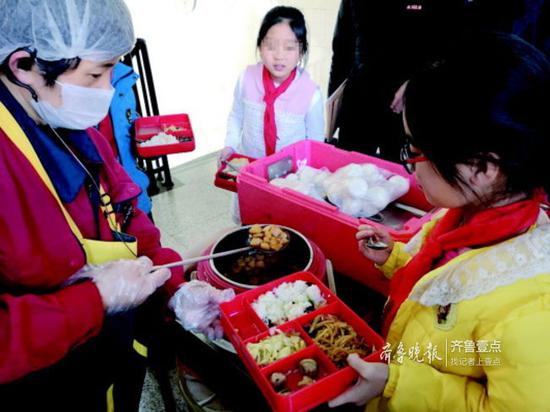 配餐单位工作人员正在给学校孩子们打饭菜,天气冷饭菜降温很快。