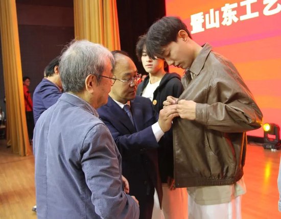 首届毕业生1973级校友、院长董占军、资深教授郭志光为学生代表佩戴校徽