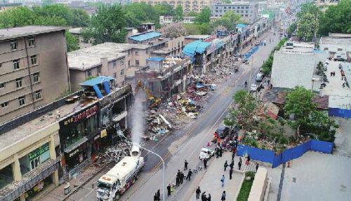 24日,在山师东路南段,大型施工设备开始拆除路西侧临街违章建筑。记者王锋 摄