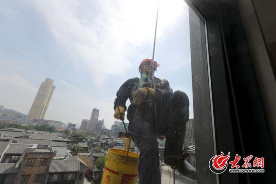 李世增認真地做著自己的工作,先是清洗,然后用水沖,面前的窗戶被擦洗得干干凈凈。大眾網記者 王長坤 李兆輝 攝