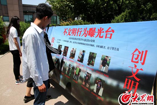 山東外國語職業學院學生在曝光臺前觀看各類不文明行為照片。
