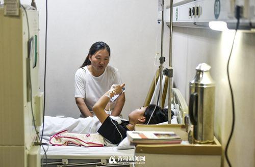 　　陪在小女儿身边的妈妈，神情显得十分疲惫