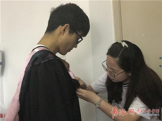 團支書為王銳穿上學士服。