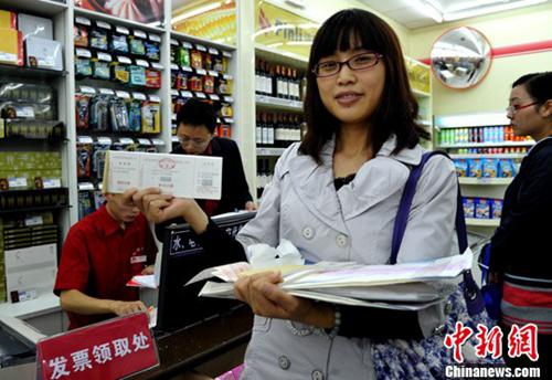 　　图为一位纳税人展示在超市刚领取的发票。中新社发 刘忠俊 摄