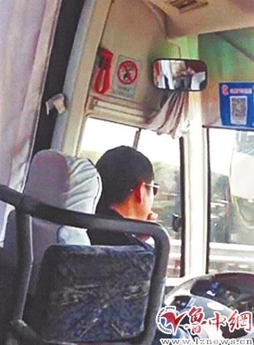 大巴车行驶过程中，司机右手握着方向盘，左手拿着瓜子往嘴里送。视频截图