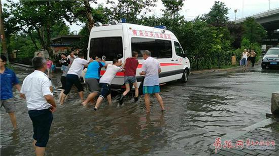 公交司機和群眾一起將救護車推出積水區